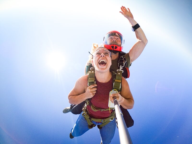 Un duo en tandem de parachutisme, l'élève exprime l'excitation, chute libre contre le soleil éclatant et ciel clair