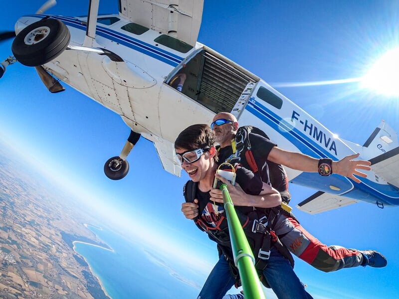Sortie d'avion en tandem, l'élève enthousiaste, vue aérienne des terres agricoles, sous un ciel bleu