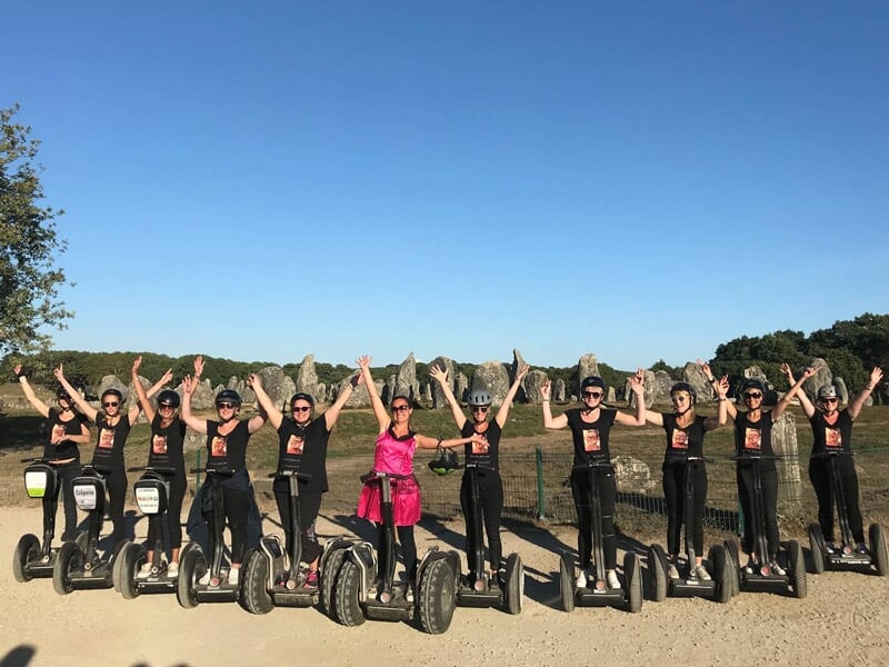 Groupe de femmes en segway sur un chemin ensoleillé, levant les bras en signe de joie.