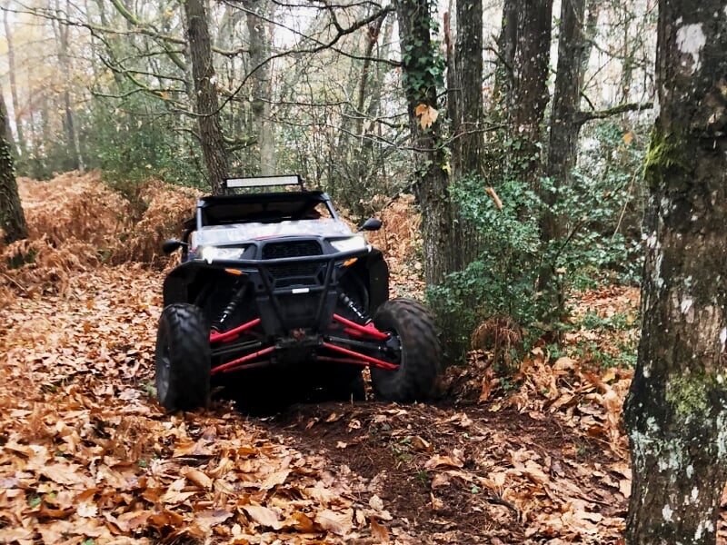 Quads stationnés sur une prairie avec des collines et des arbres verts sous un ciel clair.