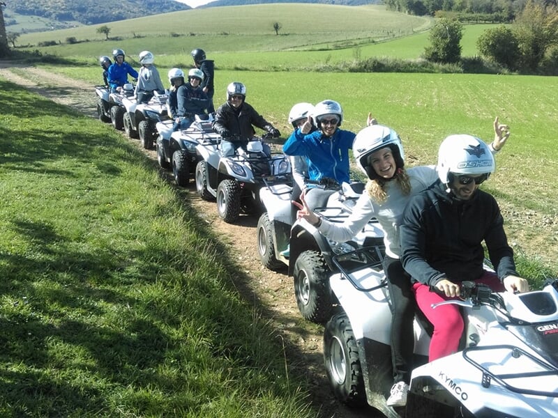 Un groupe de personnes au volant de quad à la file indienne sur un chemin à travers champs.