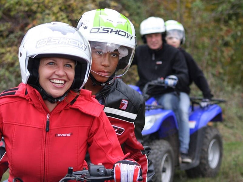 Quatre personnes portant un casque blanc font une randonnée en quad dans la nature.