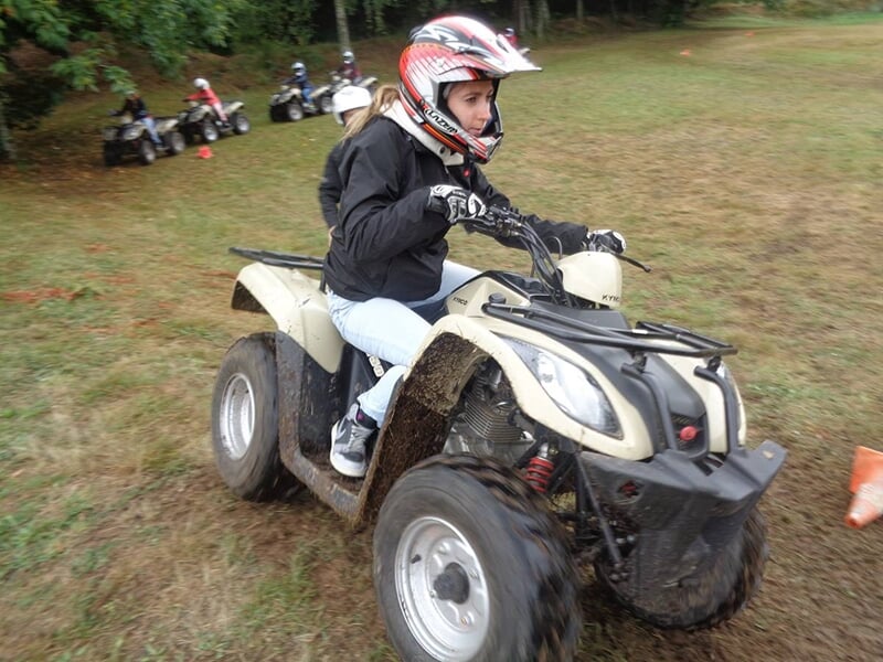 Une femme pilote un quad blanc dans un champs d'herbe verte.