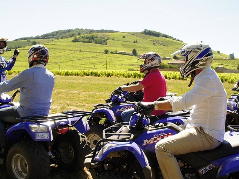 Un instructeur parle à plusieurs personnes conduisant des quads dans une nature verdoyante.