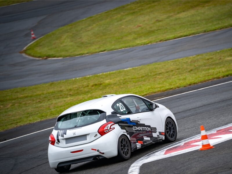 peugeot 208 racing cup en plein virage sur circuit à coté d'un pot