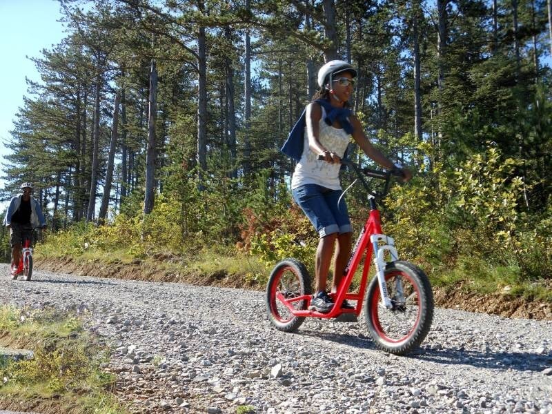 une trottinettiste sur un sentier rocailleux