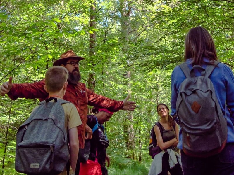 Un instructeur en forêt explique à un groupe de personnes les techniques de survie en pleine nature.
