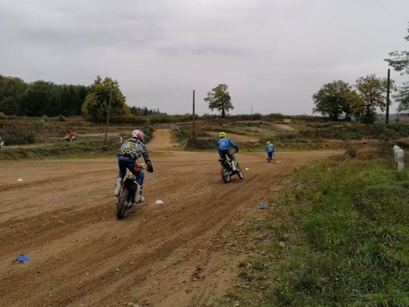 Des pilotes de motocross roulent debout sur leur engin sur une piste école