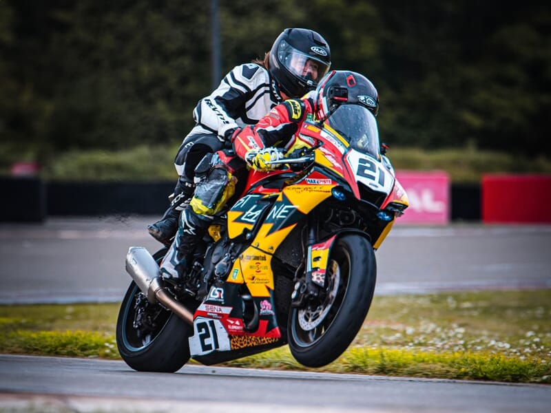 Coureur de moto en pleine accélération en combinaison jaune et rouge avec des éclaboussures sur le circuit