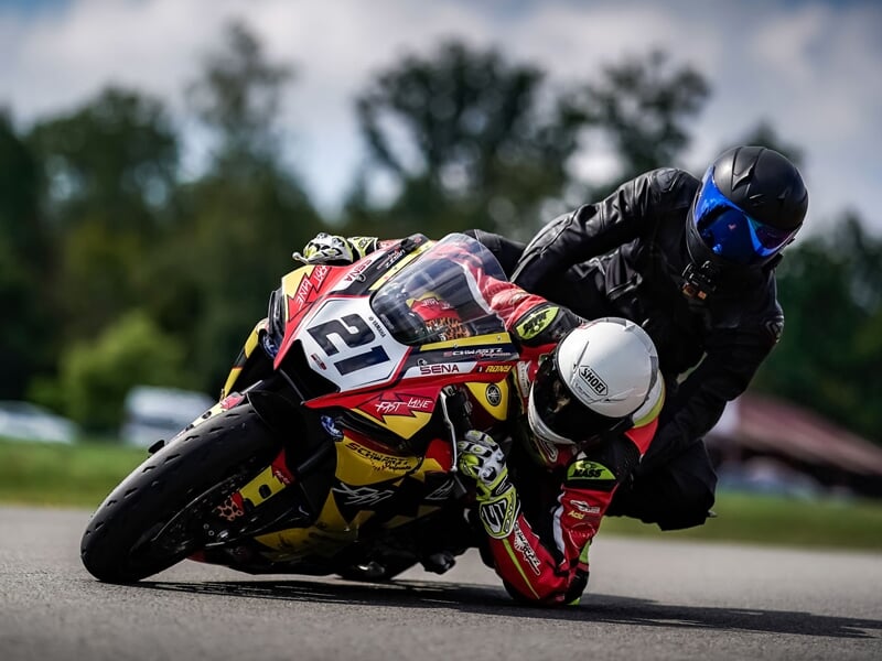 Deux motocyclistes en compétition sur piste, penchés dans un virage serré lors d'une course
