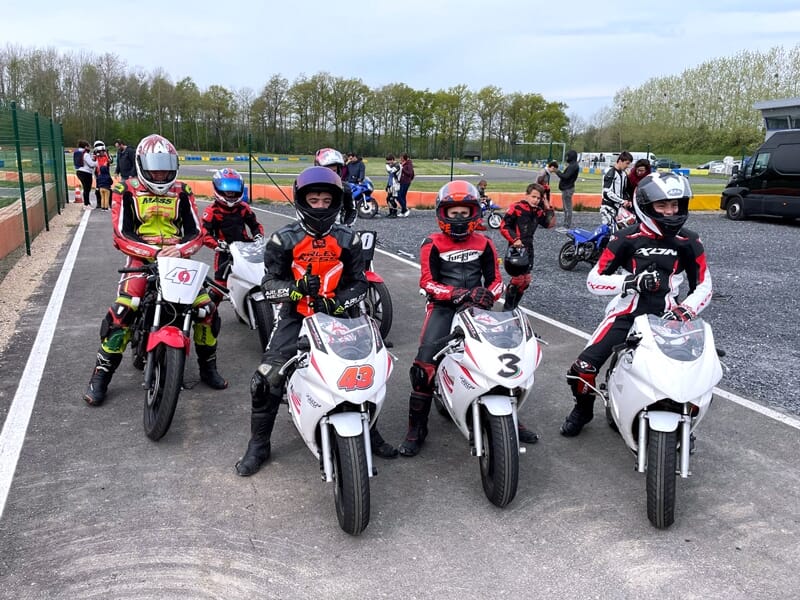 un groupe d'enfants et d'adolescents à moto se préparent à rouler sur le circuit