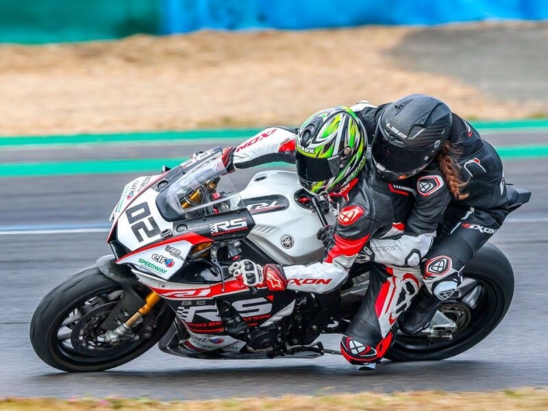 Deux pilotes en combinaison et casques roulent ensemble sur une moto sportive blanche sur le circuit de Bresse.
