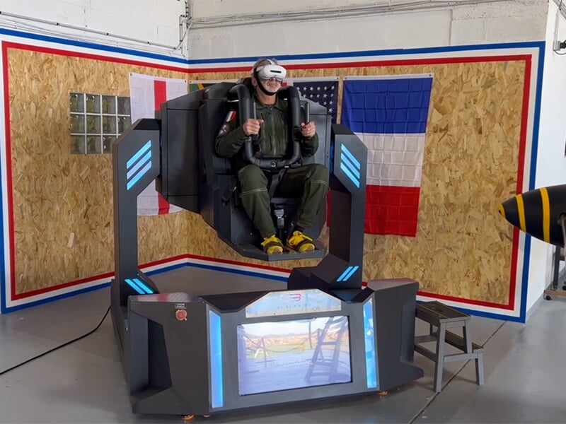 Personne assise dans le simulateur de vol gyroscopique, en position verticale, portant un casque VR.