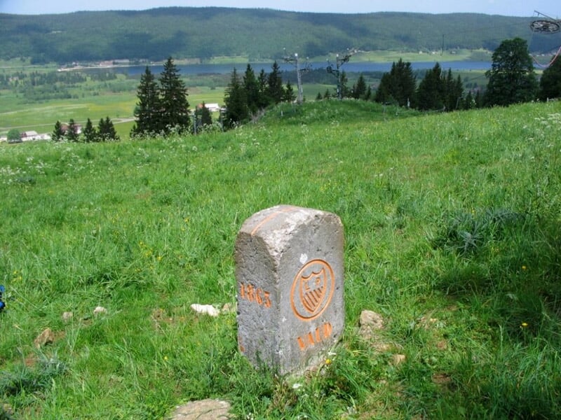 Borne en pierre gravée sur une colline verte avec vue panoramique sur la campagne environnante