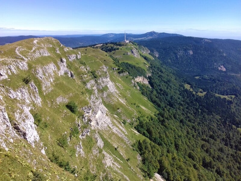 Vue aérienne d'une crête montagneuse rocheuse avec une forêt dense en contrebas et un ciel clair