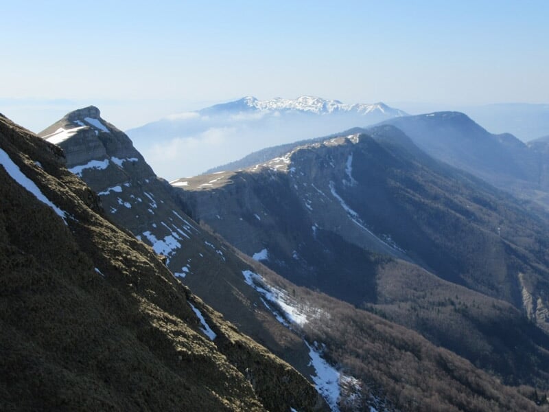 Chaîne de montagnes enneigées sous un ciel bleu avec des sommets partiellement couverts de nuages