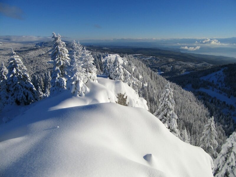 Vue panoramique de montagnes enneigées avec crêtes rocheuses et ciel bleu clair au-dessus