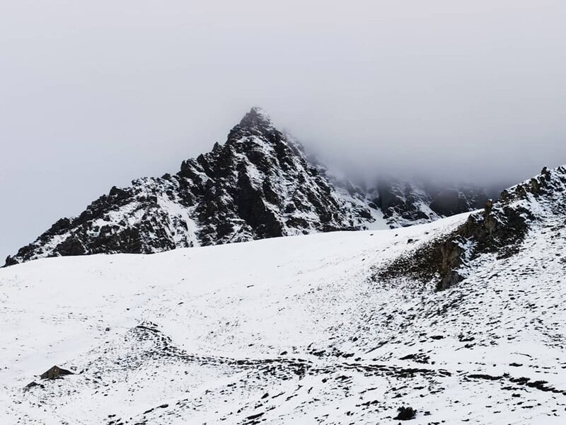 Montagne enneigée avec sommet pointu partiellement couvert par des nuages dans le massif de Val Cenis.