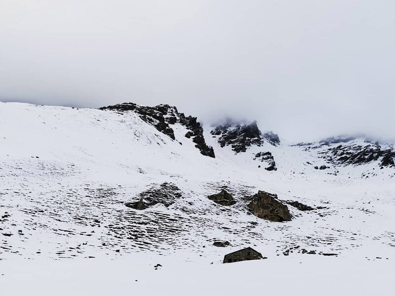 Paysage de haute montagne enneigée avec rochers et ciel gris dans la région de Val Cenis.