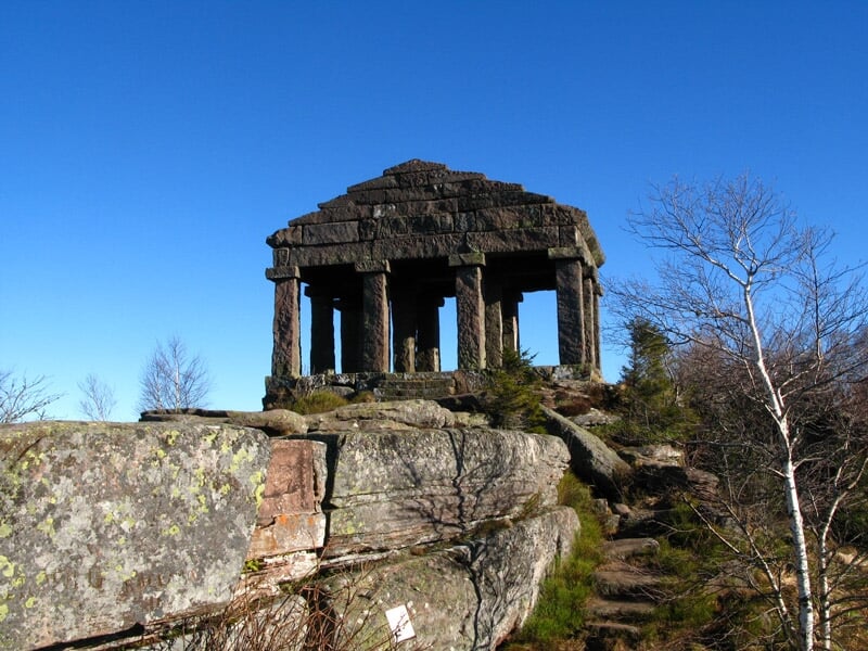 Monument en pierre avec colonnes sur un rocher entouré d'arbres sans feuilles