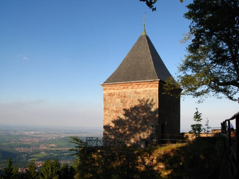 Petit bâtiment en pierre avec toit pointu sur une colline avec vue sur la plaine