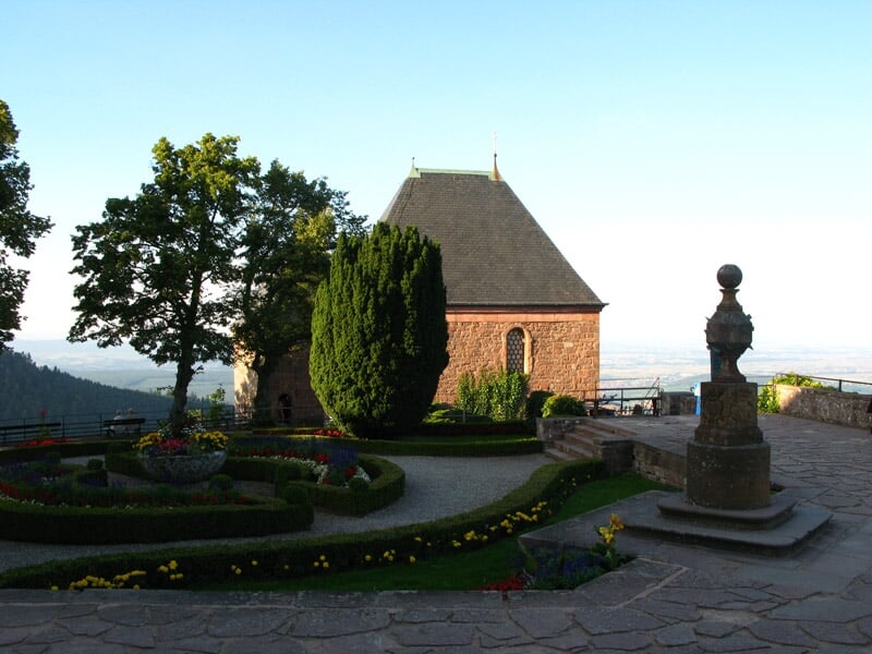 Jardin fleuri et bien entretenu devant un bâtiment en pierre avec toit en ardoise