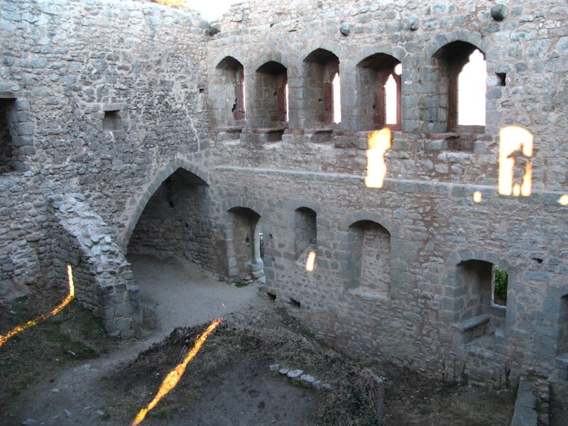 Intérieur en ruines d'un château médiéval avec murs en pierre et fenêtres sans vitres