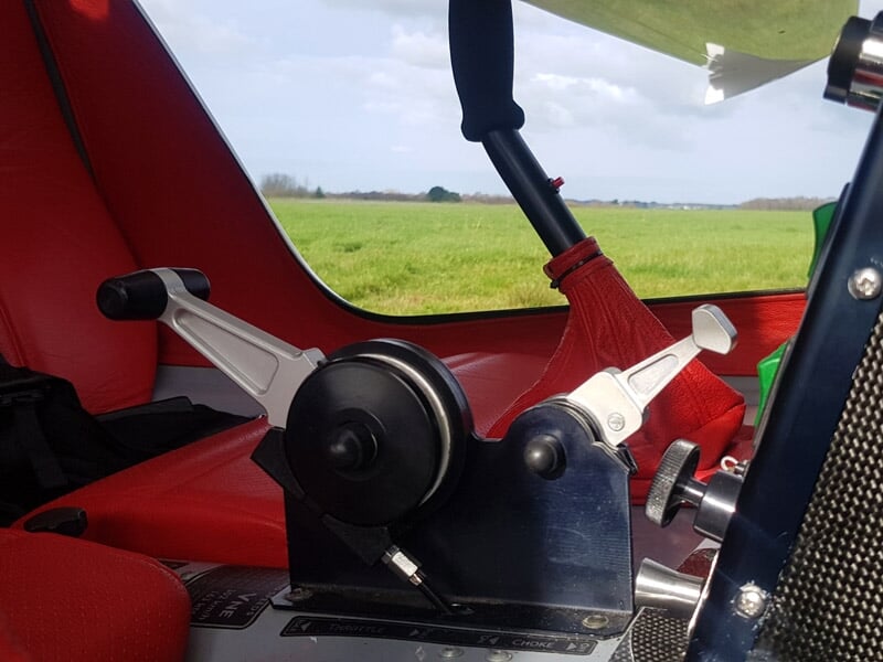 Détail du mécanisme de commande et siège rouge à l'intérieur d'un petit avion léger.