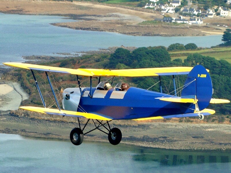 le biplan stampe bleu avec des ailes jaunes en plein vol