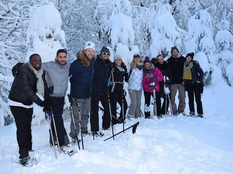 Groupe de personnes posant pour une photo lors d'une randonnée en raquettes dans la neige.