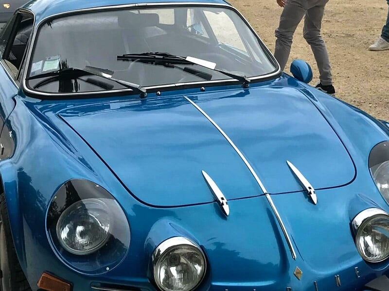 Gros plan sur le capot d'une voiture de sport bleue classique avec des phares ronds et des détails chromés.
