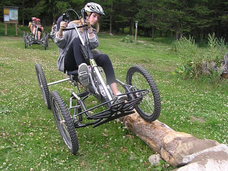 Jeune femme portant un casque pilote un quadbike tout terrain sur un chemin herbeux en forêt.