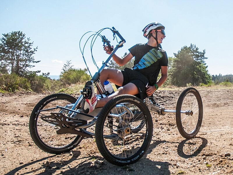 Homme en tenue sportive sur un quadricycle tout terrain regarde sur le côté en pleine nature ensoleillée.