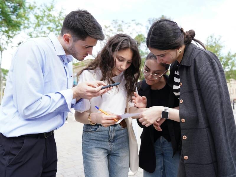 Quatre jeunes concentrés en extérieur, collaborant pour résoudre une énigme d'un escape game près du Tréport.