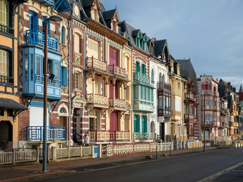 Alignement de maisons colorées et anciennes avec balcons en bois, typiques de l'architecture de Mers-les-Bains.