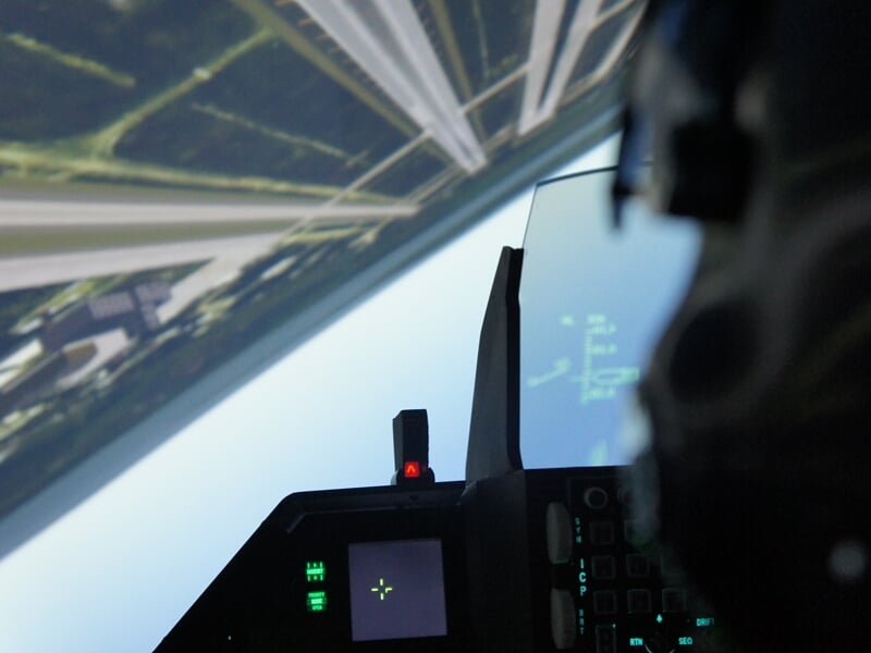 Vue immersive depuis un simulateur de vol, montrant un paysage en perspective inclinée à travers le pare-brise.