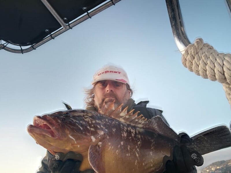 Homme tenant un gros poisson pris lors d'une sortie de pêche en mer à Monaco, Alpes-Maritimes.