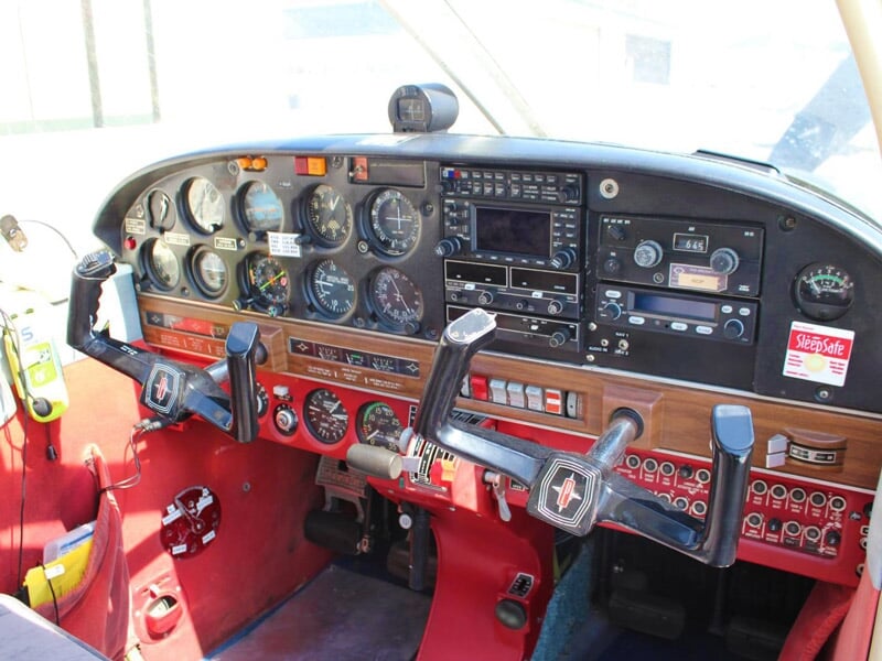 Cockpit d'un avion léger avec plusieurs instruments de pilotage et commandes visibles en rouge et noir.