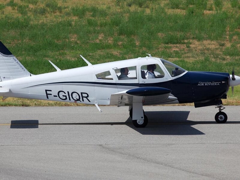Avion léger blanc et bleu immatriculé F-GIQR sur une piste d'aérodrome avec un pilote à bord.