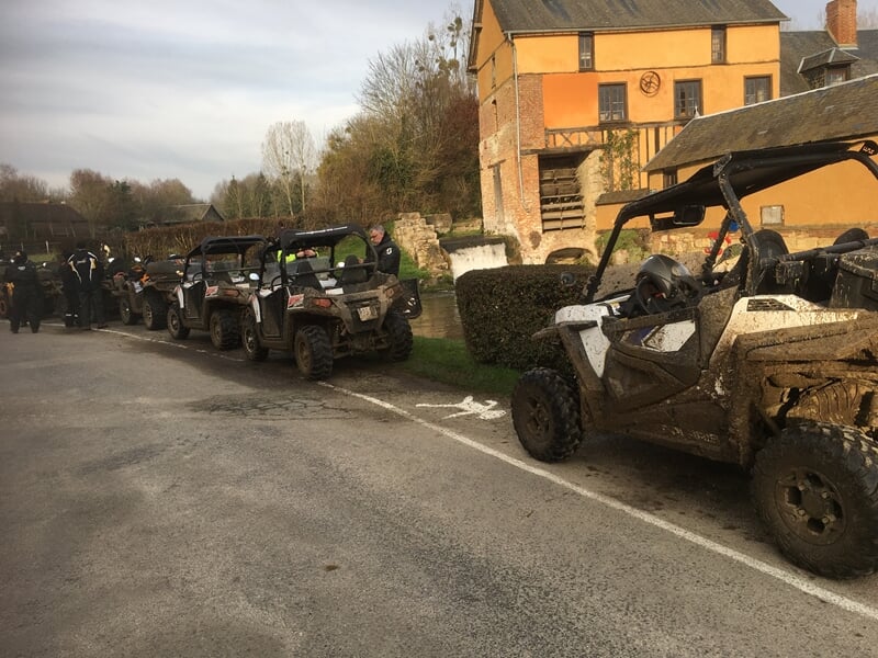 Quads alignés sur une route près d'un bâtiment ancien, prêts pour une randonnée au Mont Saint Adrien.