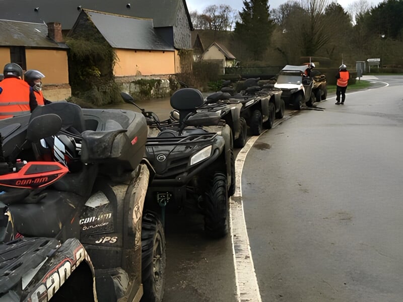 Rangée de quads garés le long d'une route avec des conducteurs en gilets orange, prêts pour une randonnée.