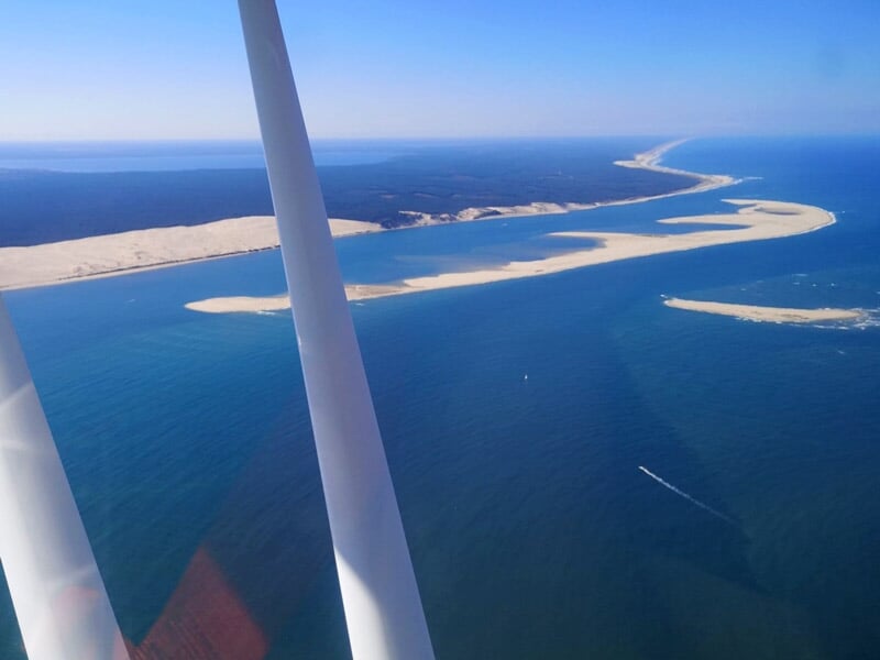 Paysage vu du ciel montrant une plage de sable fin et des bras de mer entre des dunes.