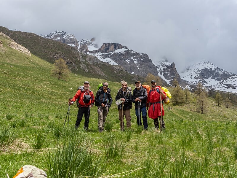 Un groupe de randonneurs posent devant des montagnes enneigées en pleine nature