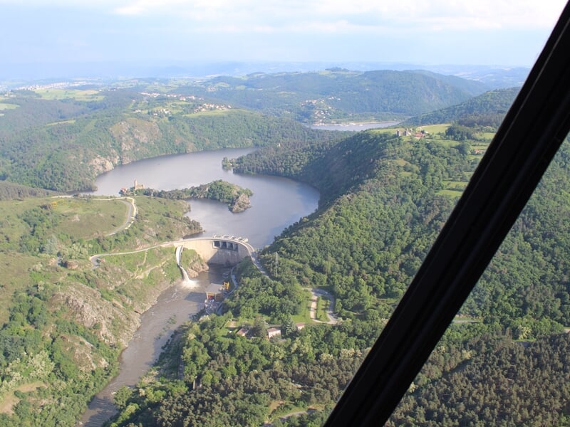 Rivière sinueuse traversant une vallée verdoyante vue depuis un hélicoptère en vol.