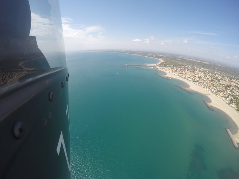 Vue panoramique d'une baie avec plages, maisons et mer calme sous un ciel clair.