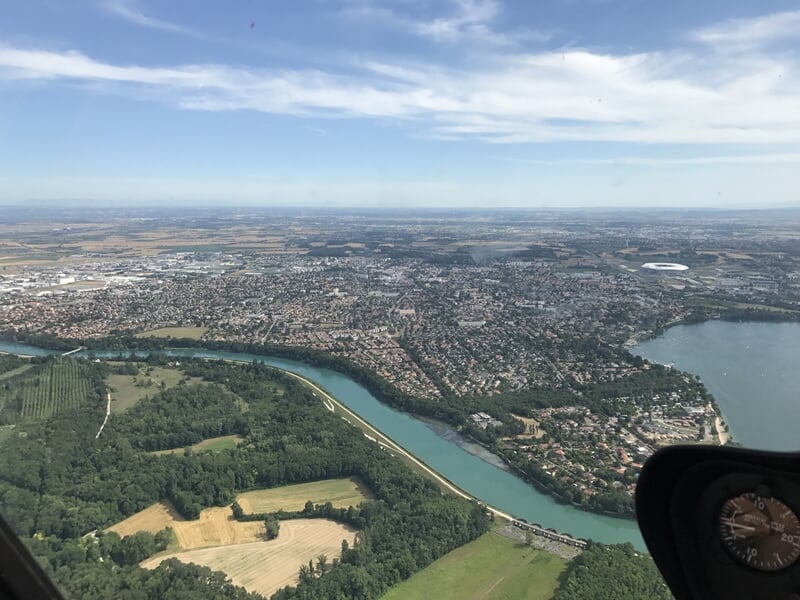 Paysage de la région lyonnaise avec le Rhône visible, serpentant entre des zones boisées et des terres agricoles