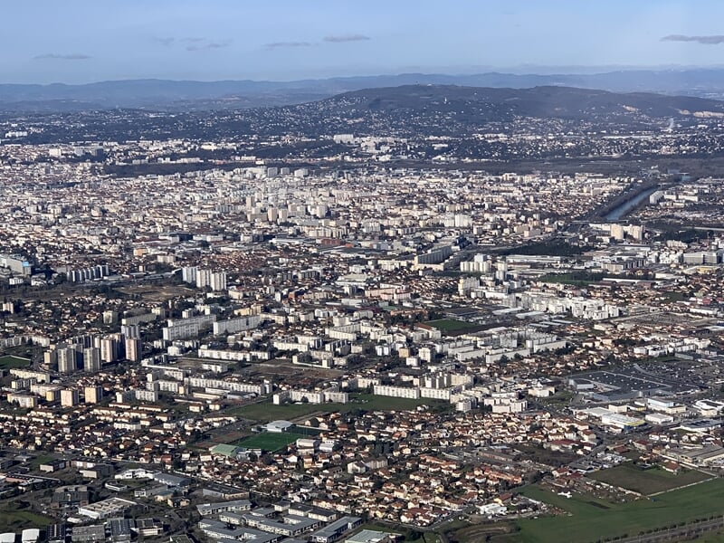 Panorama urbain vu d'un hélicoptère montrant une grande ville avec nombreux bâtiments.