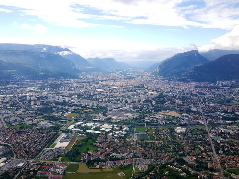 Vue aérienne d'une ville avec quartiers résidentiels et montagnes enneigées en arrière.