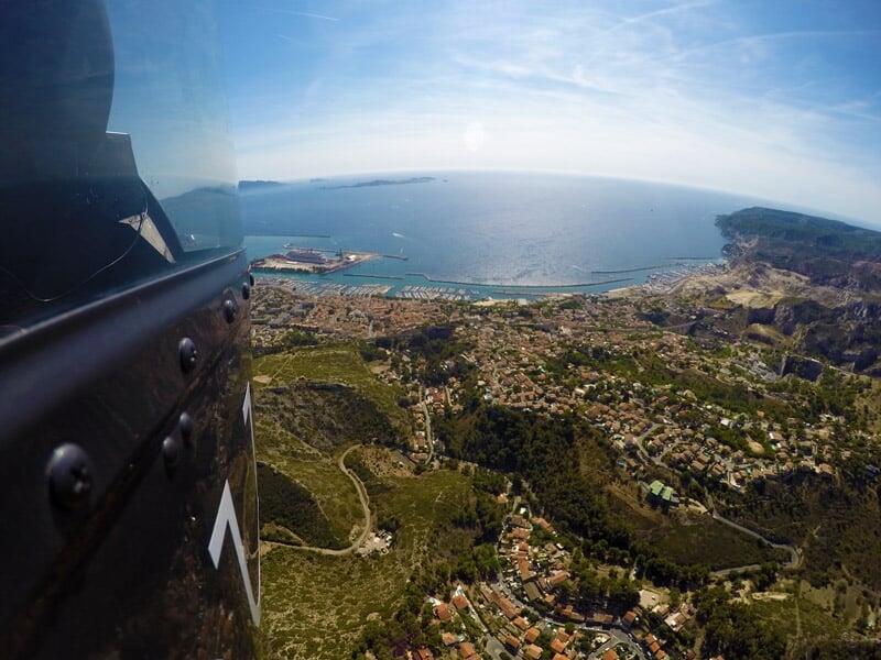 Vue aérienne d'une ville portuaire avec bâtiments, routes et mer visible au loin.