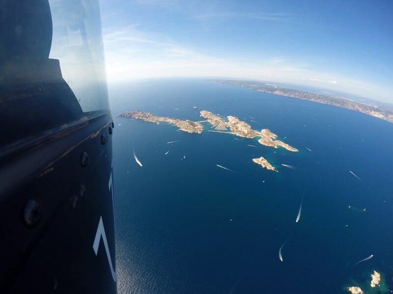 Vue panoramique d'une ville côtière avec bâtiments, plages et mer turquoise.